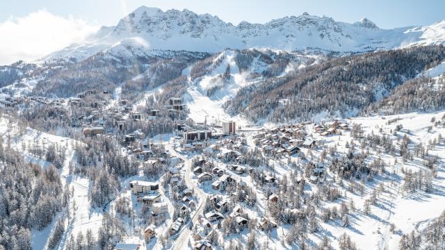 Vue drone sur Vars les Claux durant l'hiver avec en fond les sommets enneigés de l'Eyssina