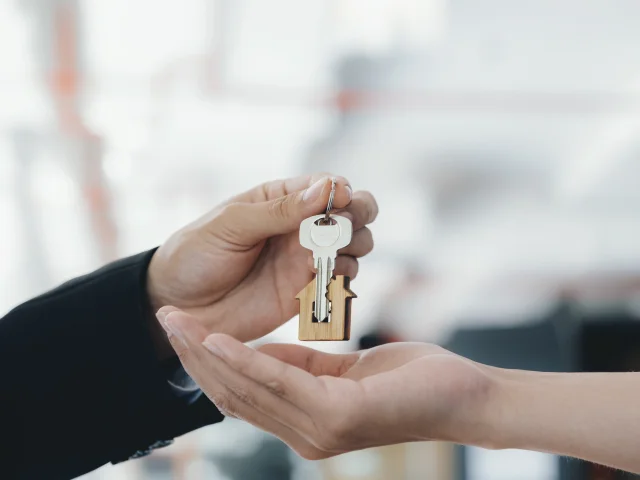 Real estate agent holding key with house shaped keychain.  Real estate, buy or sale or moving home or renting property. Mortgage and business concept.